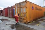 Funkcjonariusz pomorskiej KAS w bazie kontenerowej przed kontenerem z nielegalna dostawą,