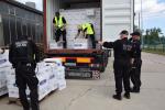 Funkcjonariusze celno-skarbowi wyładowujący nielegalne papierosy z kontenera