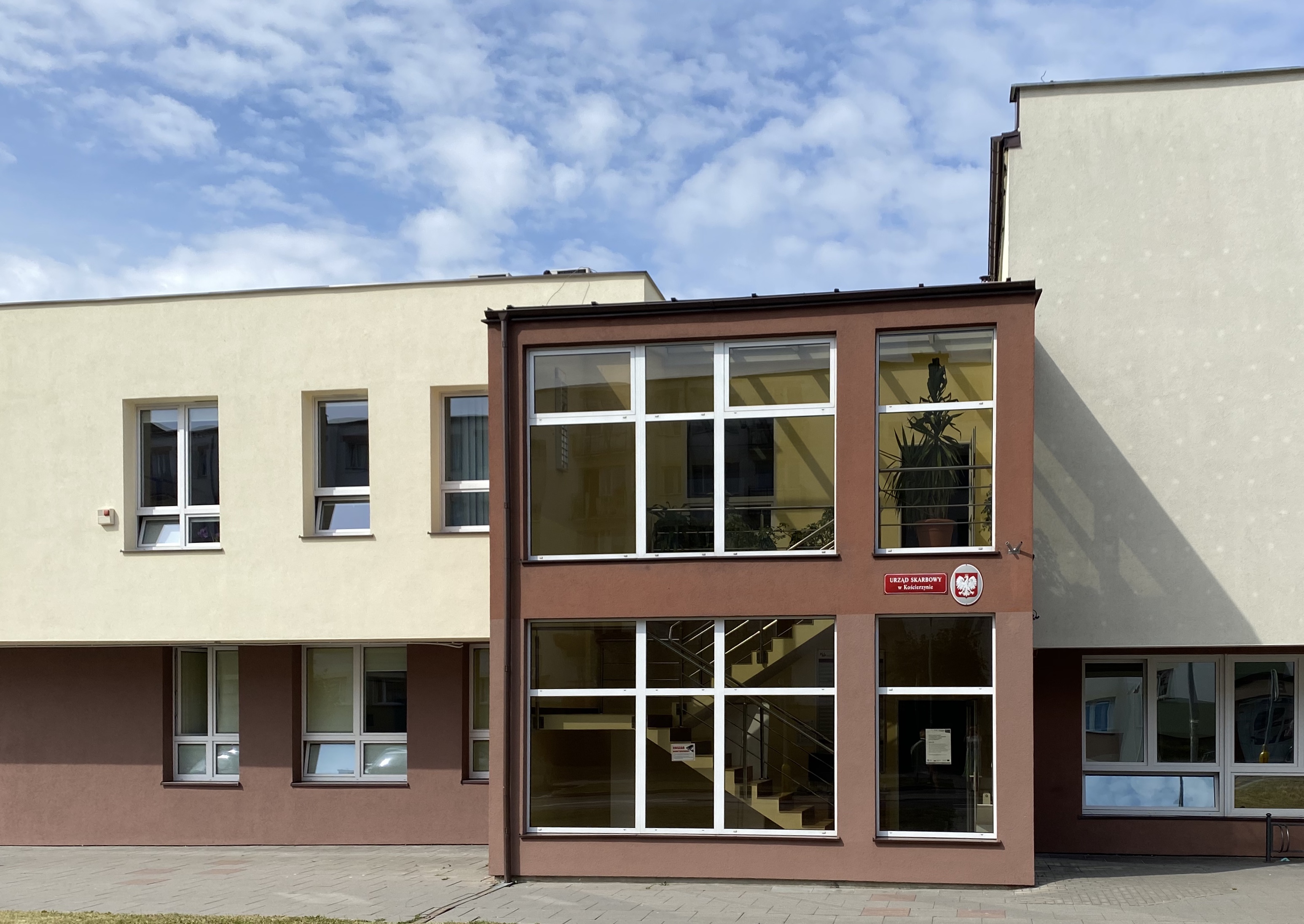 Wejście do budynku, w którym znajduje się siedziba Urzędu Skarbowego w Kościerzynie. Elewacja w kolorze brązowym.