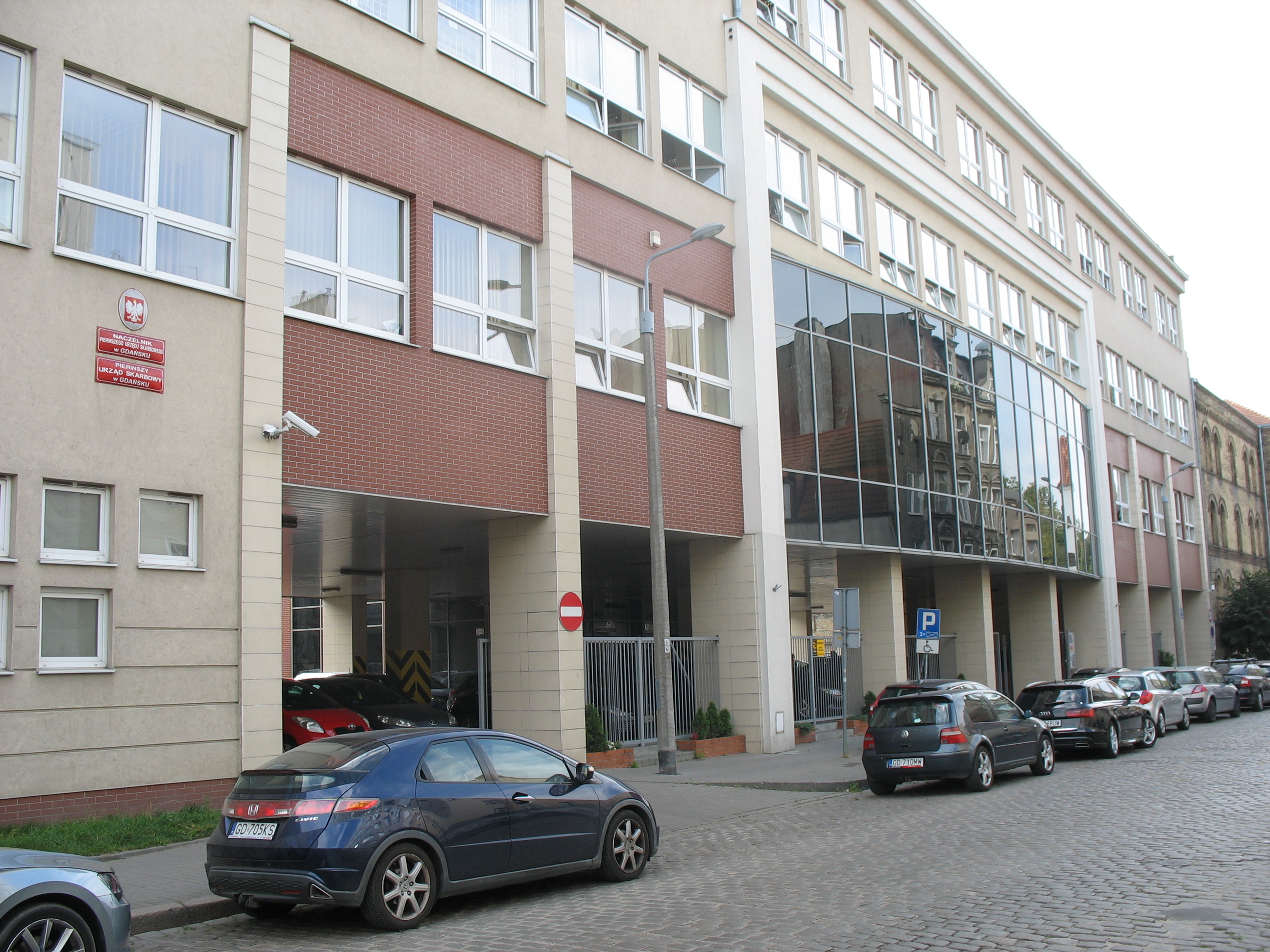 Budynek o beżowo-brązowej elewacji, w której znajduje się siedziba Pierwszego Urzędu Skarbowego w Gdańsku