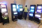 Pomieszczenie, w którym znajdują się automaty do gier hazardowych. Po środku stoi tyłem funkcjonariusz.