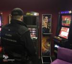 Funkcjonariusz Służby Celno-Skarbowej odwrócony tyłem w salonie z automatami do gier hazardowych.