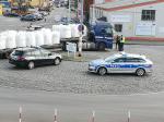 Na placu stoją dwa samochody: Służby Celno-Skarbowej i Policji. Na drugim planie stoi ciężarówka oraz funkcjonariusze Służby Celno-Skarbowej i Policji.