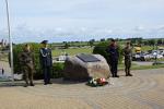 Pomnik poległych celników w Tczewie. Obok stoją funkcjonariusze różnych służb. Pod pomnikiem leżą kwiaty.