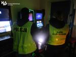 Dwaj funkcjonariusze Służby Celno-Skarbowej i Policji stoją tyłem przy automatach