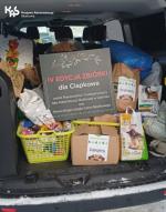 Bagażnik samochodu wypełniony darami dla schroniska dla zwierząt. Na wierzchu tabliczka 