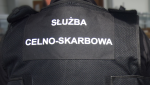 Funkcjonariusz celno-skarbowy odwrócony plecami. Widać na plecach napis Służba Celno- Skarbowa.