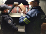 Funkcjonariusz KAS i CBŚP wyciągają ze schowka chłodniczego paczki z kokainą