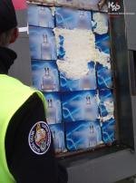 Funkcjonariusz Służby Celno-Skarbowej stoi przed kontenerem.
W kontenerze znajdują się kartony z alkoholem.