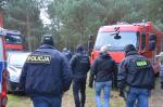 Policjanci i funkcjonariusze Służby Celno-Skarbowej podchodzą do samochodów w lesie